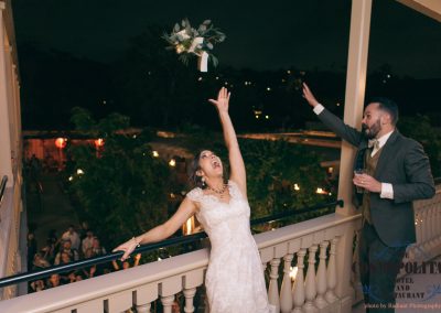 a groom celebrating his wife tossing her bouquet off the balcony.
